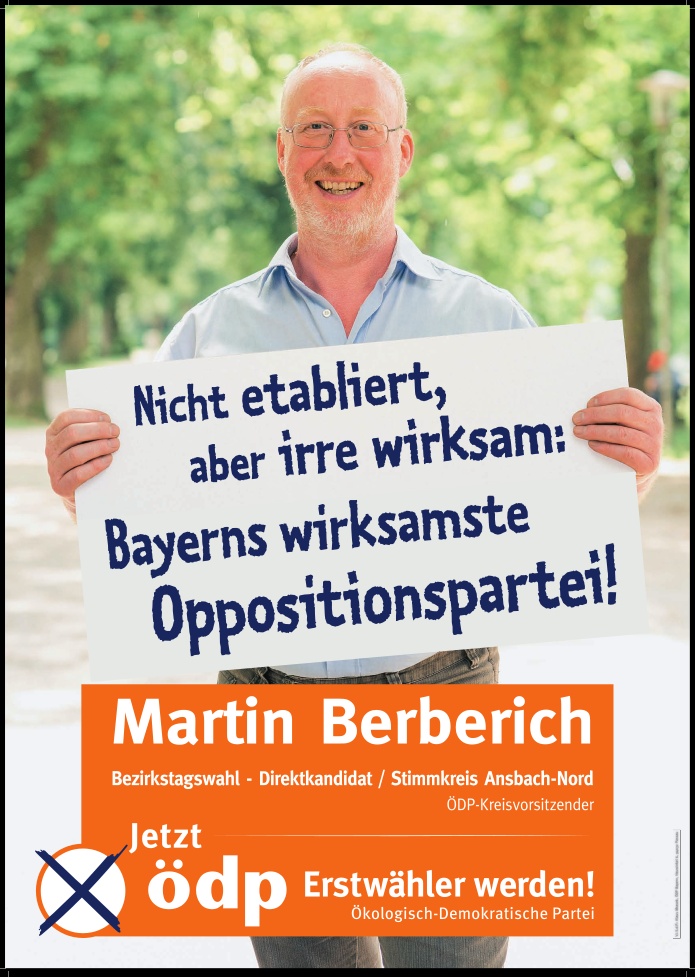 Das Bild zeigt Martin Berberich vor Bäumen in einem Park. Er hält ein Plakat in der Hand mit der Aufschrift „Nicht etabliert, aber irre wirksam: Bayerns wirksamste Oppositionspartei!“. Darunter eine Überblendung des Bildes in orange mit der Aufschrift „Martin Berberich – Bezirkstagswahl-Direktkandidat / Stimmkreis Ansbach-Nord – ÖDP-Kreisvorsitzender – Jetzt ödp Erstwähler werden! Ökologisch-Demokratische Partei“